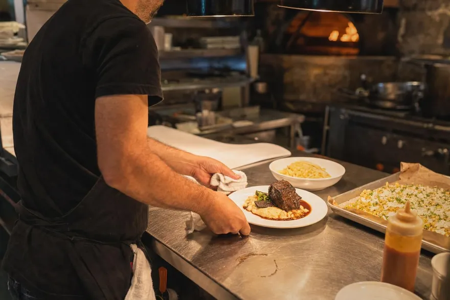A line cook plating a dish at the pass in the 42 Fusion kitchen
