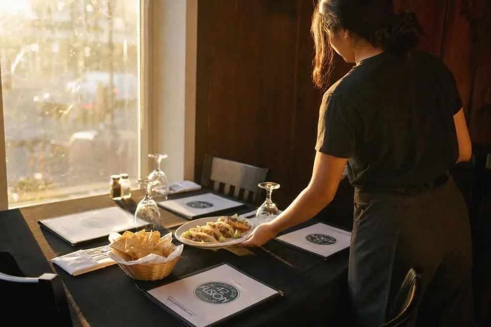 A server setting two plates on a window table at 42 Fusion